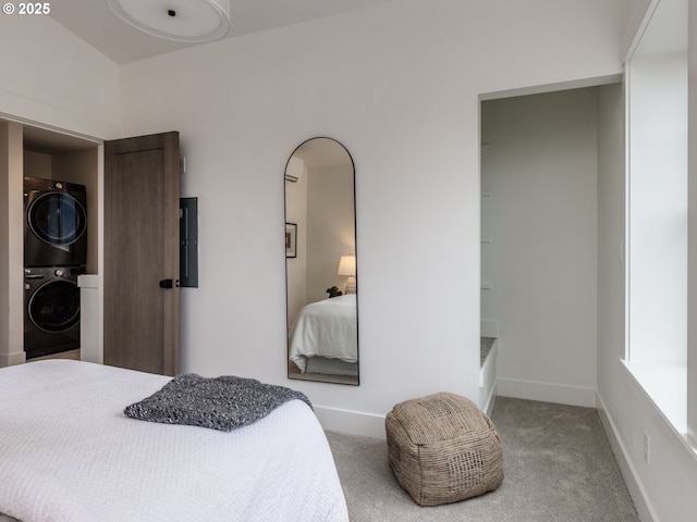 bedroom with baseboards, stacked washer and dryer, and carpet