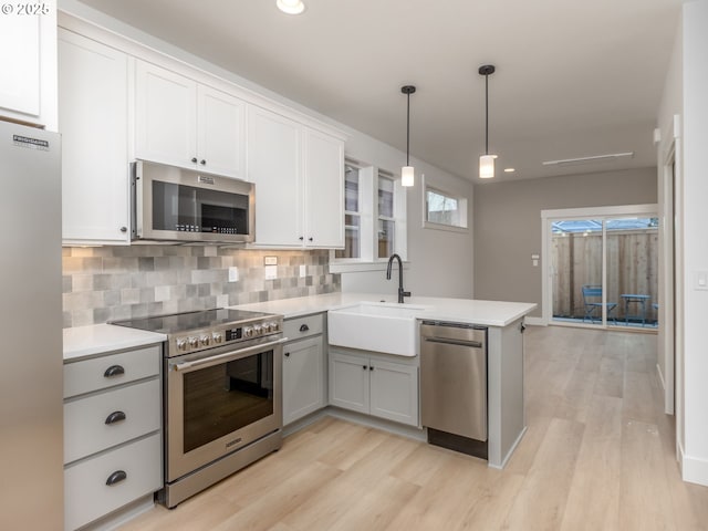 kitchen with a sink, appliances with stainless steel finishes, a peninsula, and light countertops