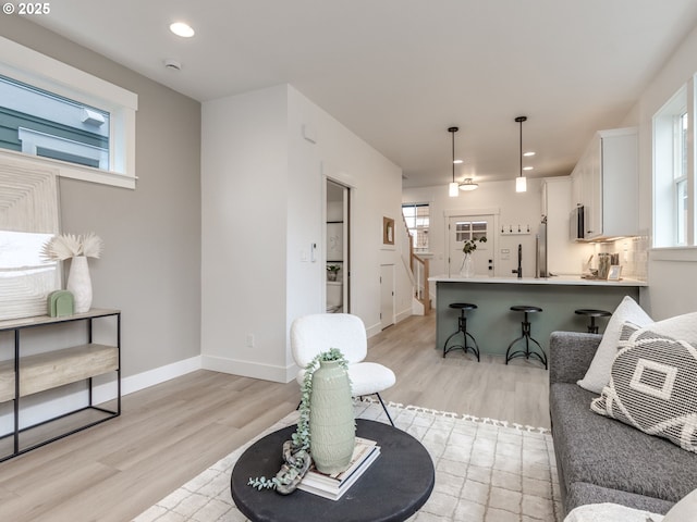 living room featuring recessed lighting, baseboards, and light wood-style floors