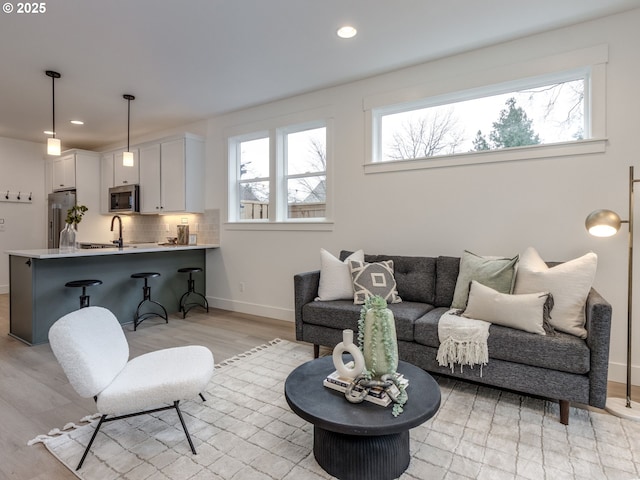 living room with recessed lighting, light wood-type flooring, and baseboards