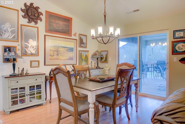 dining area with vaulted ceiling, light hardwood / wood-style floors, and an inviting chandelier