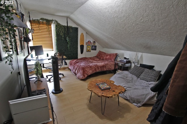 bedroom with lofted ceiling, a textured ceiling, and light wood-type flooring