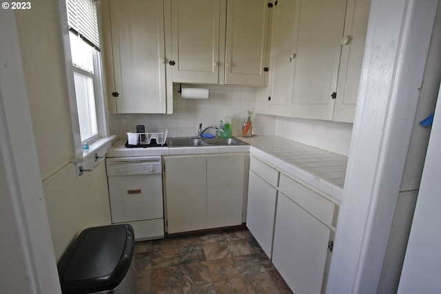 kitchen featuring tile countertops, white cabinetry, sink, backsplash, and white dishwasher