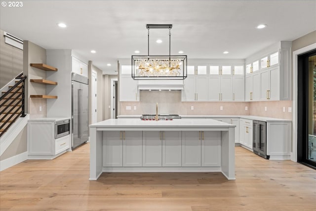 kitchen with a center island with sink, white cabinetry, appliances with stainless steel finishes, and light hardwood / wood-style flooring