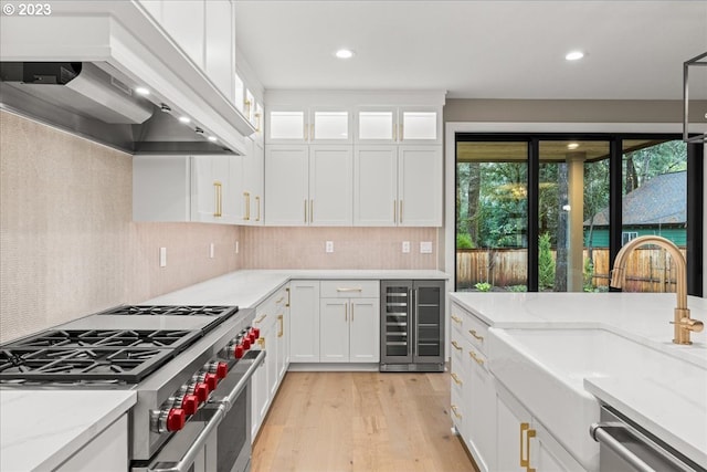 kitchen with wine cooler, white cabinetry, custom range hood, and appliances with stainless steel finishes