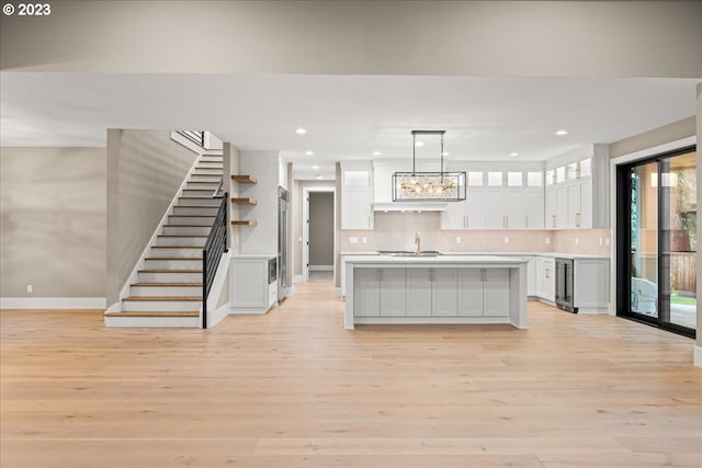 kitchen featuring white cabinets, pendant lighting, light hardwood / wood-style floors, and a kitchen island with sink