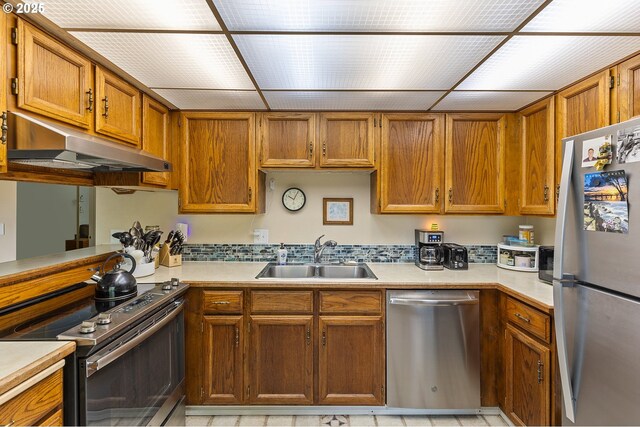 kitchen featuring a sink, appliances with stainless steel finishes, under cabinet range hood, and light countertops