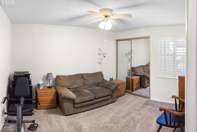 carpeted living room featuring ceiling fan and a textured ceiling