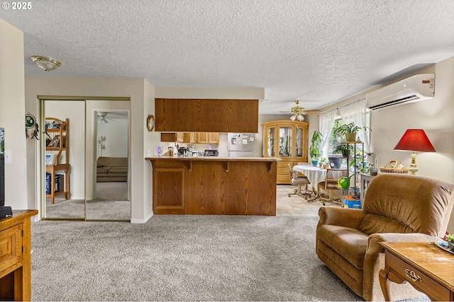 kitchen with an AC wall unit, a ceiling fan, light carpet, and freestanding refrigerator