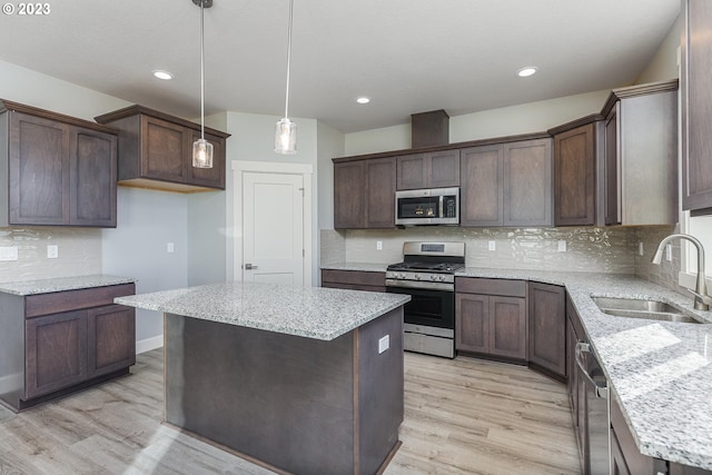 kitchen with tasteful backsplash, a center island, stainless steel appliances, light hardwood / wood-style floors, and sink