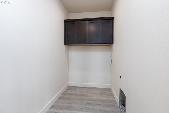 clothes washing area featuring hookup for an electric dryer, light hardwood / wood-style flooring, and cabinets