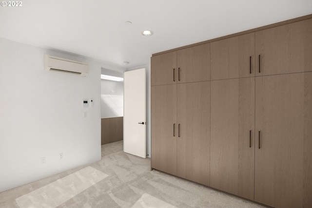 unfurnished bedroom featuring a wall unit AC, a closet, and light colored carpet