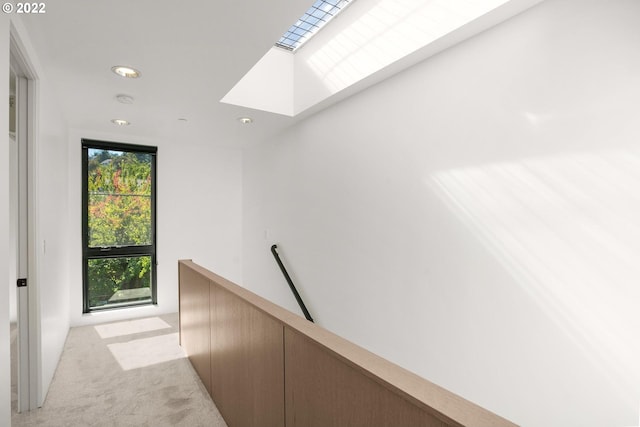 corridor with light carpet and a skylight