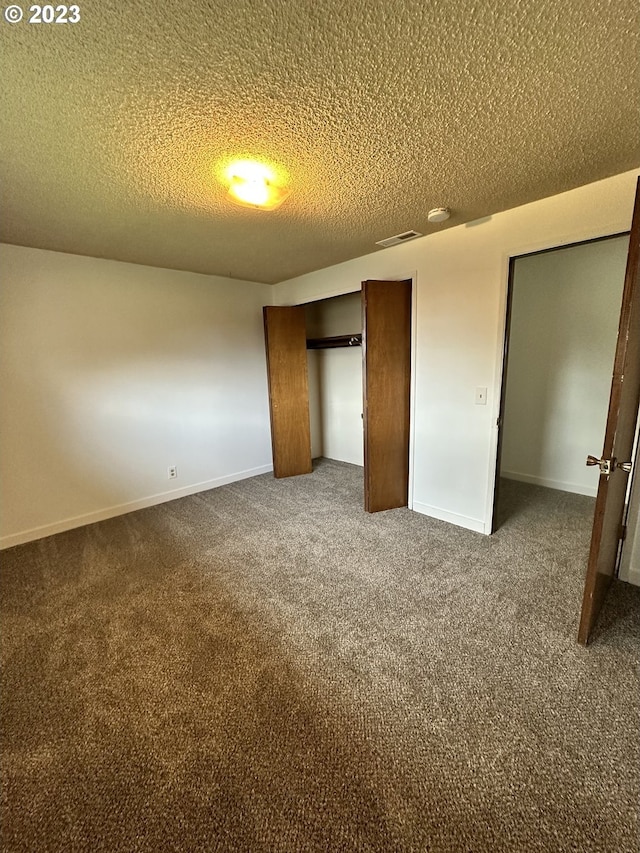 unfurnished bedroom with dark carpet and a textured ceiling