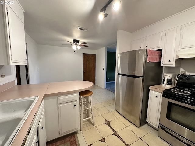 kitchen with sink, light tile patterned floors, ceiling fan, appliances with stainless steel finishes, and white cabinetry