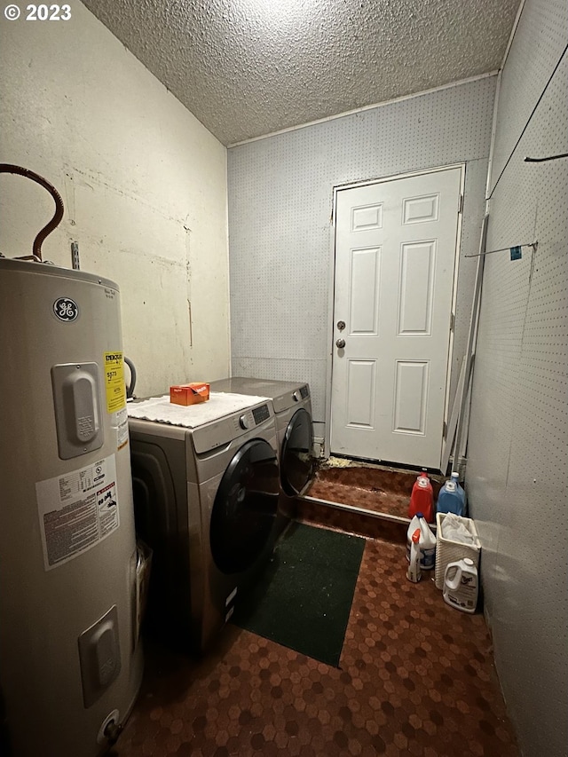 laundry area with washing machine and clothes dryer, electric water heater, and a textured ceiling