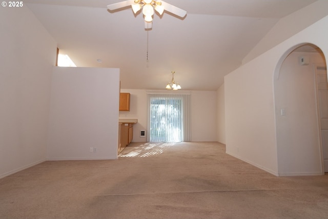 unfurnished living room featuring vaulted ceiling, ceiling fan with notable chandelier, and light colored carpet