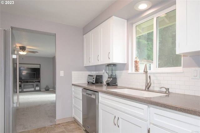 kitchen with sink, stainless steel appliances, white cabinets, and light colored carpet