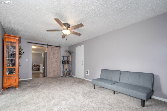 sitting room featuring ceiling fan, a barn door, carpet flooring, and a textured ceiling