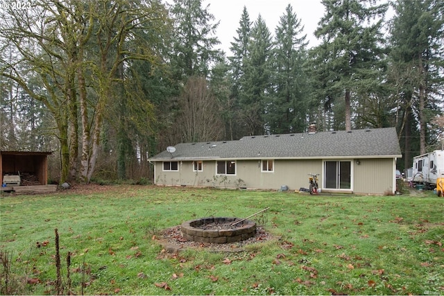 back of property featuring an outdoor fire pit and a yard