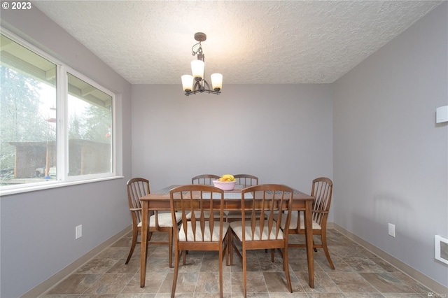 dining area with a textured ceiling and a notable chandelier