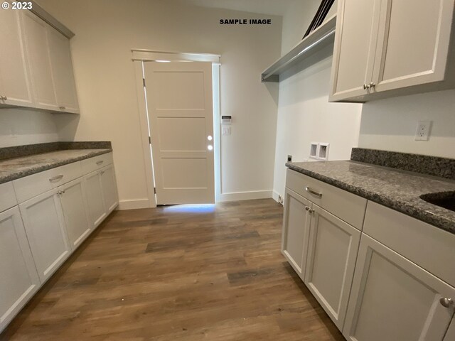 kitchen with dark hardwood / wood-style flooring, white cabinetry, and dark stone counters