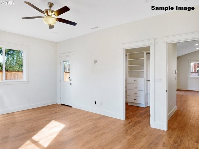 unfurnished bedroom with ceiling fan, lofted ceiling, a spacious closet, and light hardwood / wood-style floors