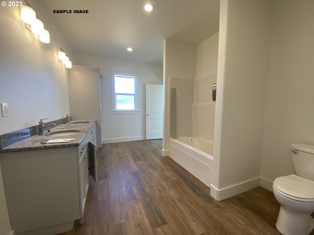 bathroom with dual vanity, toilet, and wood-type flooring