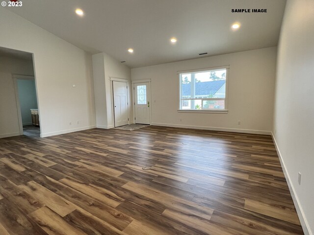 unfurnished room featuring lofted ceiling and dark wood-type flooring