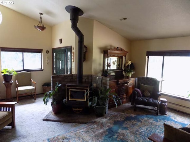 living room featuring carpet flooring, a wood stove, and lofted ceiling