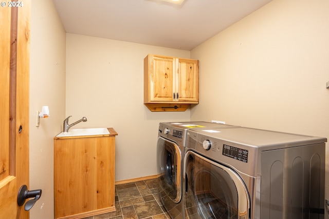 clothes washing area with washer and dryer, cabinets, and sink