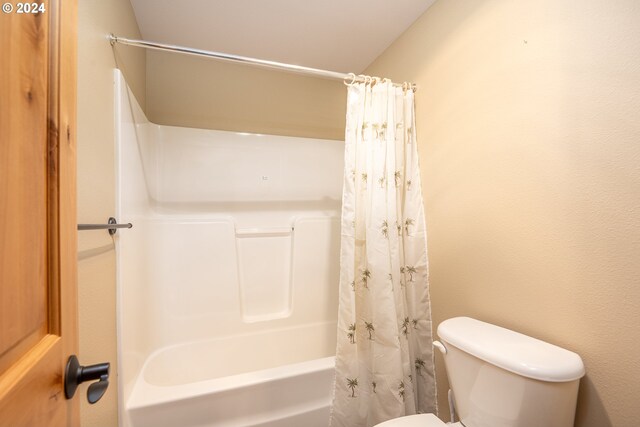 bathroom featuring toilet and shower / tub combo with curtain