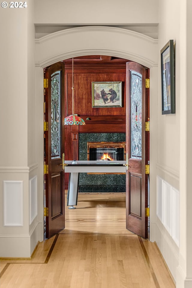 entrance foyer with a decorative wall, wainscoting, a fireplace, and light wood-type flooring