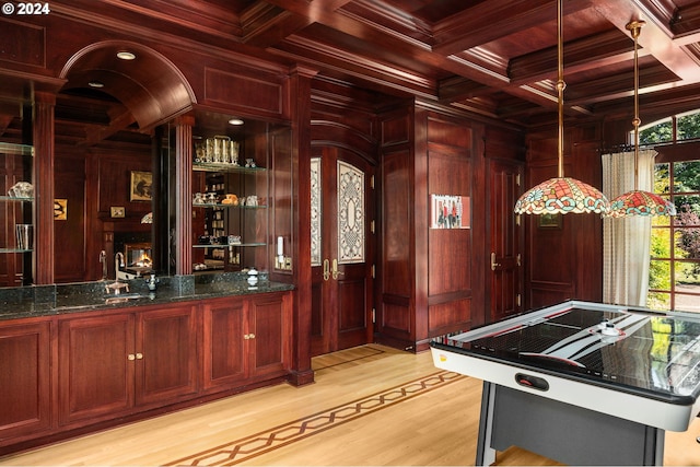 bar with beam ceiling, coffered ceiling, wooden walls, crown molding, and light wood finished floors