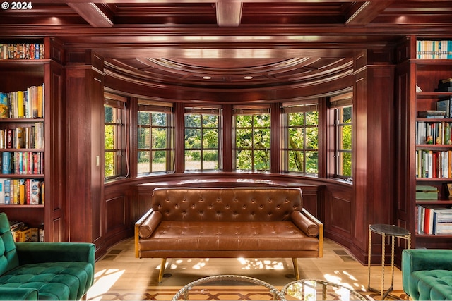 living area featuring a wealth of natural light, wood walls, coffered ceiling, and ornamental molding