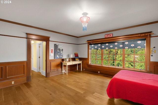 bedroom featuring a wainscoted wall, ornamental molding, and light wood finished floors