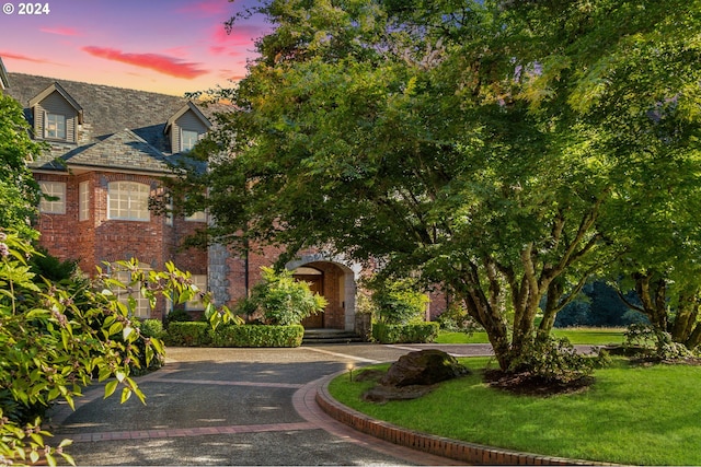 view of front of property featuring brick siding, driveway, and a front lawn