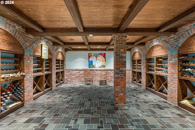 wine area featuring beamed ceiling, wood ceiling, and brick wall