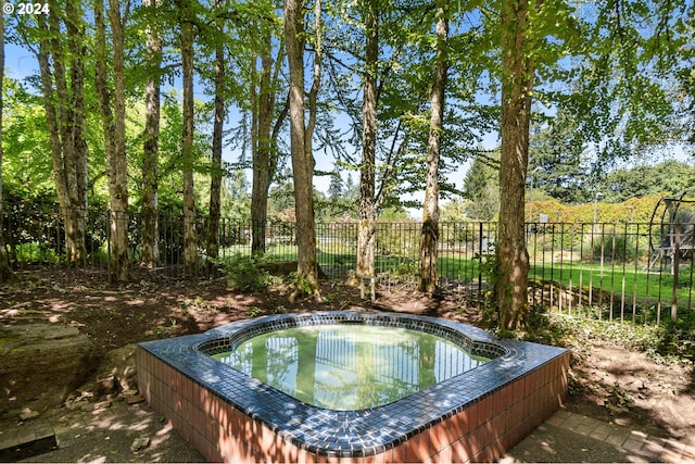 view of pool with an outdoor hot tub and fence