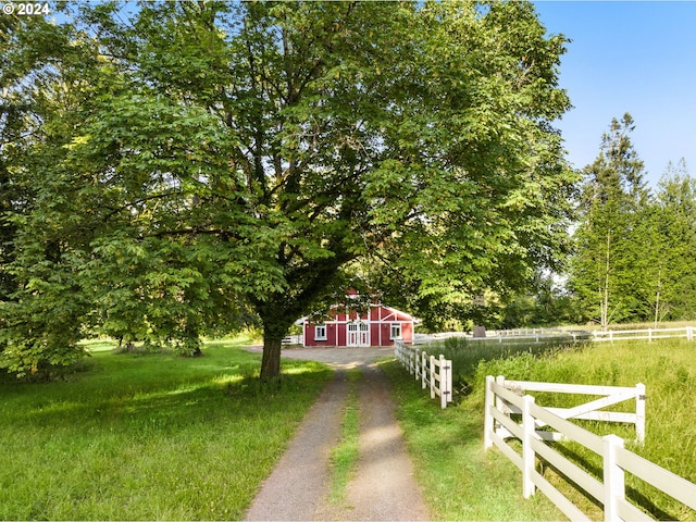 view of front of house with a barn, driveway, an outdoor structure, and fence