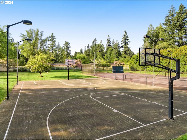 view of basketball court with community basketball court, fence, and a lawn