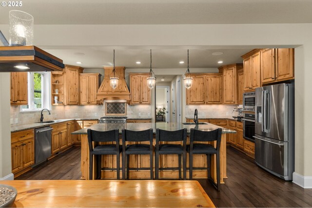 4425 SW 47th Dr, Portland, OR 97221 - kitchen featuring stainless steel appliances, premium range hood, dark wood-type flooring, a sink, and an island with sink