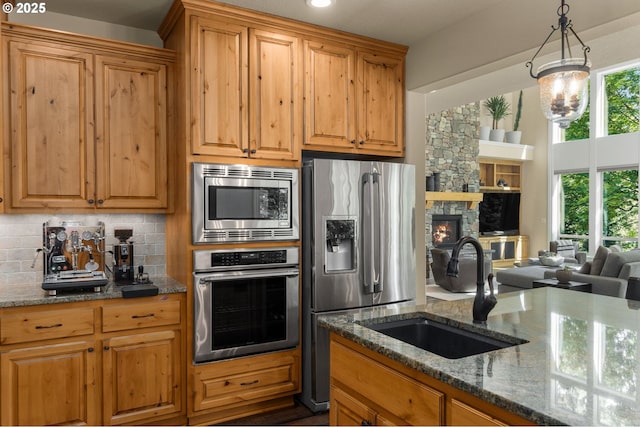 4425 SW 47th Dr, Portland, OR 97221 - kitchen featuring stainless steel appliances, a sink, decorative backsplash, dark stone counters, and plenty of natural light