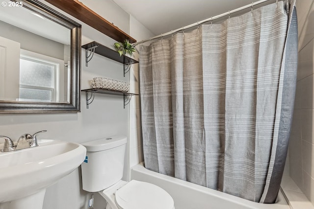 full bathroom with toilet, shower / bath combo with shower curtain, and a sink