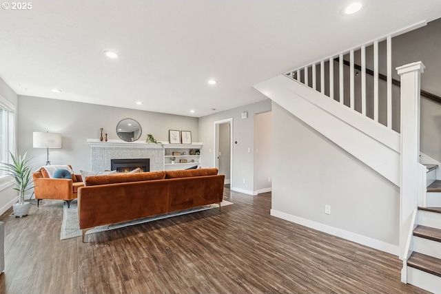 living area featuring baseboards, stairway, a lit fireplace, recessed lighting, and dark wood-style flooring