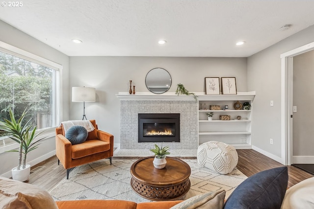 living room featuring recessed lighting, baseboards, wood finished floors, and a tiled fireplace