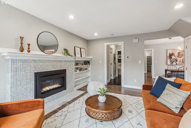 living room featuring a tiled fireplace, recessed lighting, wood finished floors, and baseboards