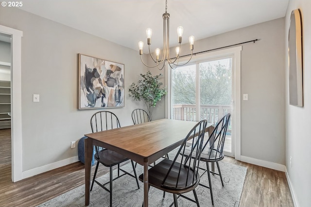 dining room with baseboards, a notable chandelier, and wood finished floors