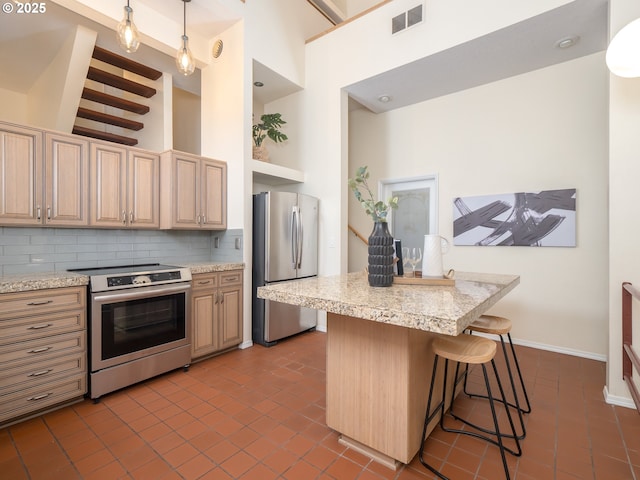 11135 SW Novare Pl, Tigard, OR 97223 - kitchen with stainless steel appliances, a kitchen bar, dark tile patterned floors, decorative backsplash, and a high ceiling