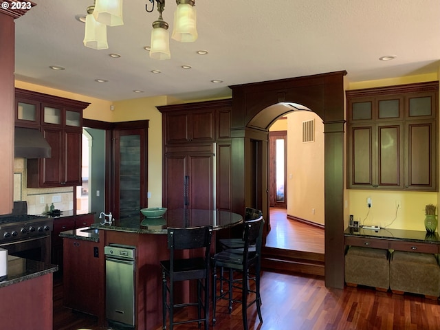 kitchen featuring dark hardwood / wood-style floors, stove, ventilation hood, and paneled built in refrigerator